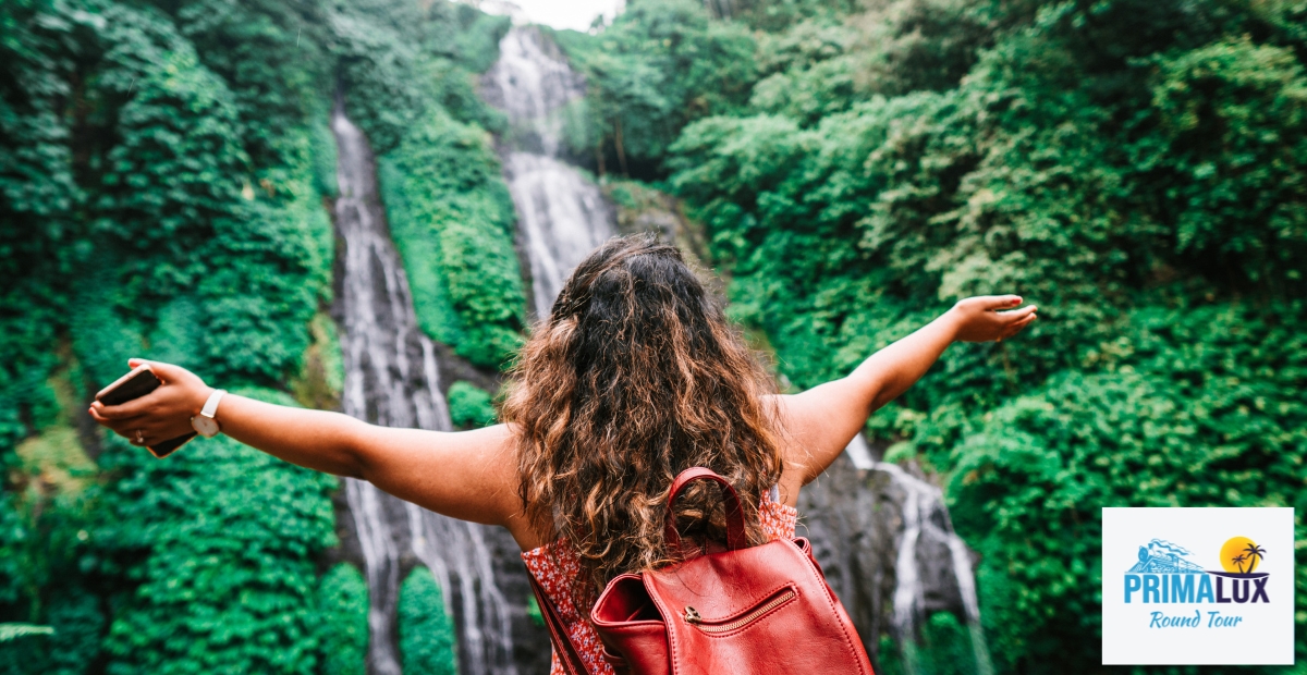 Woman with arms outstretched in front of a waterfall